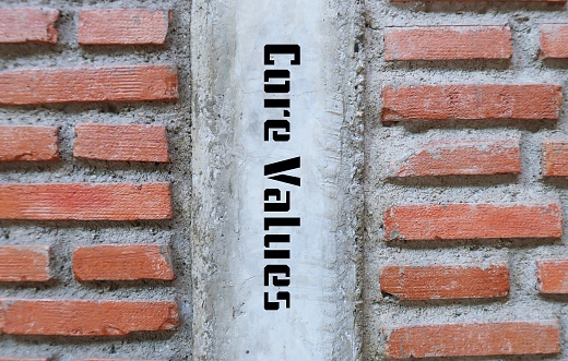 Brick wall with handwritten inscription in the middle CORE VALUES, means set of fundamental beliefs, ideals or practices which is direction of how to conduct life or career