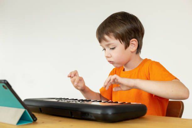 A 6-year-old boy is learning to play a synthesizer using a digital tablet