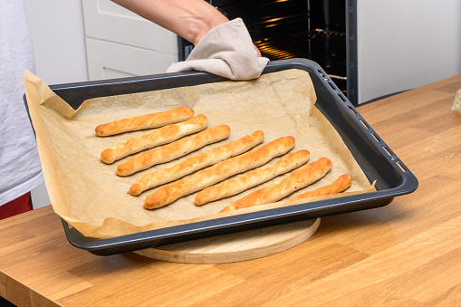 A baking tray lined with baking paper with yeast sticks held in your hands closeup