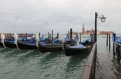gondolas moored in the port of Venice and in the background the Basilica of San Giorgio during high tide