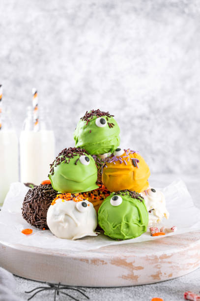 istock Homemade funny monster mini cakes or cake pops in a colored chocolate glaze and sugar sprinkles. Halloween treat on a concrete background. 1698384708
