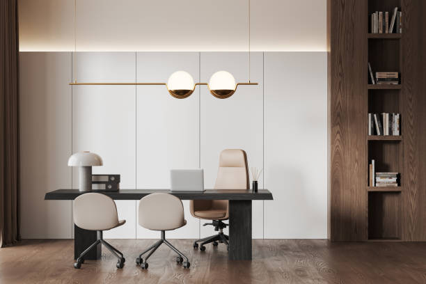 istock Stylish office interior with chairs and table, laptop and shelf with books 1698404364