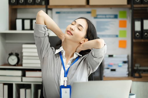 Businesswoman is doing a stretchy posture due to sitting in the office for too long, office syndrome concept.