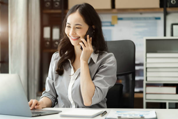 istock Business women talk mobile phones update tasks with milestones progress planning while working on laptop computers, online business, work from home, teleworking concept. 1698423282