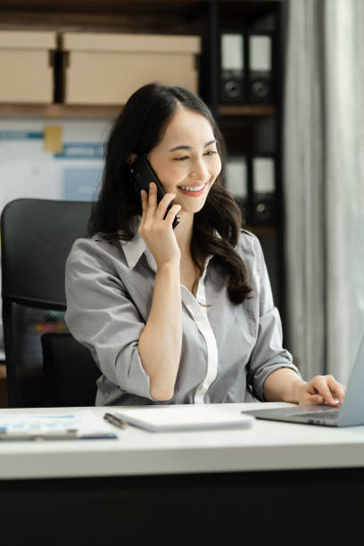 istock Business women talk mobile phones update tasks with milestones progress planning while working on laptop computers, online business, work from home, teleworking concept. 1698423520