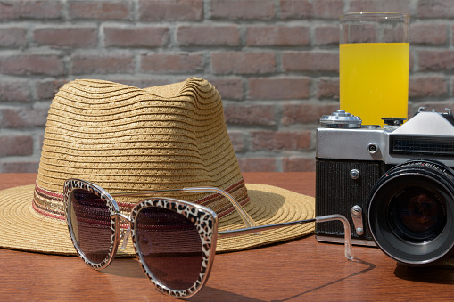 An old camera with sunglasses and a straw hat with brim. Still life
