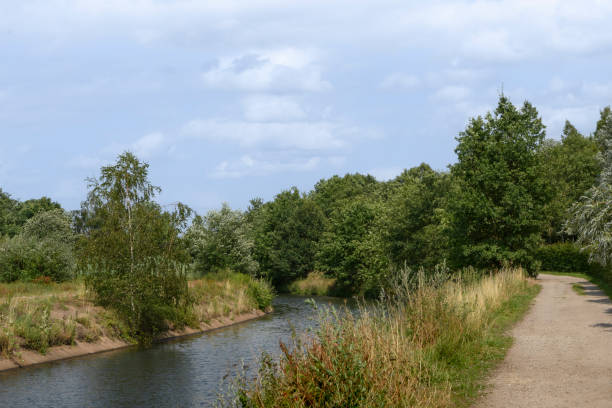 istock Summer countryside landscape. Trees, a river and a path going into the distance 1698453264