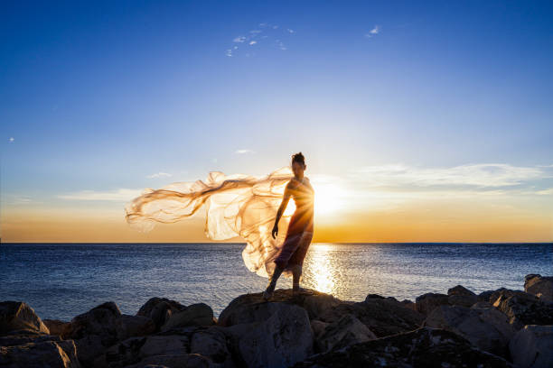 Ballerina dancing with thin nylon on the rocks.