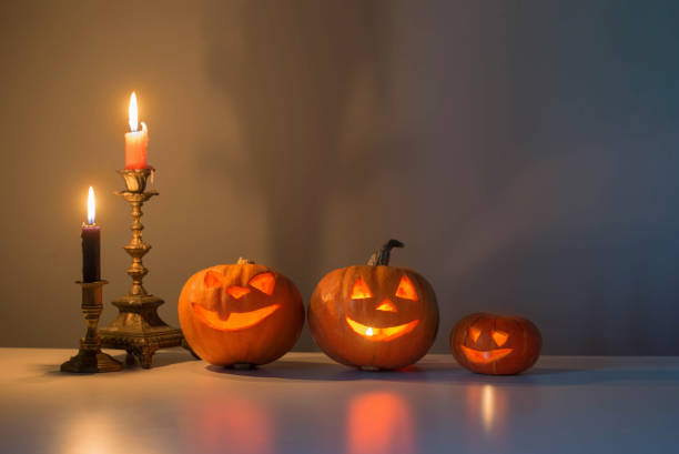 istock halloween pumpkins with burning candles on white table 1698473059