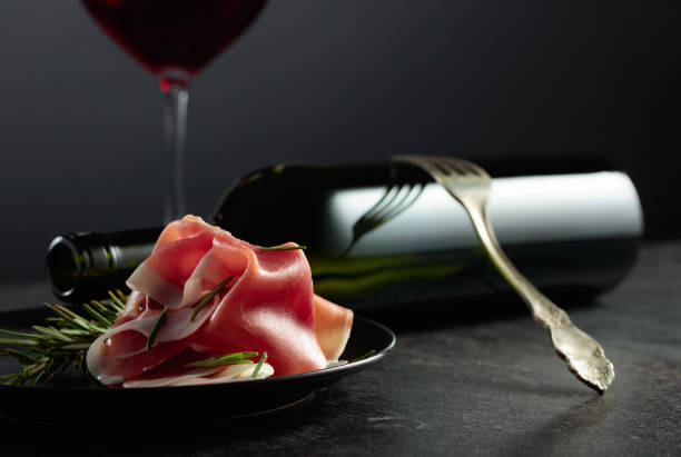 istock Prosciutto with rosemary and red wine on a black background. 1698496257