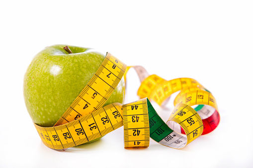 green apple and measure tape- diet food, healthy eating, fitness concept