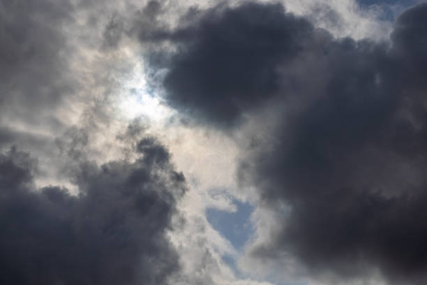 zenith pointed incoming storm cloudscape with heavy clouds and sun between them, full-frame real life photo.