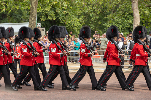 June 17th, during King Charles birthday, Trooping the Colour parade. Royal guards wearing bear fur hats marching during the parade. Bystanders watching in the background.