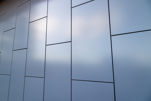 Outside wall of building covered with grayish blue painted metal rectangular panels - full-frame background.