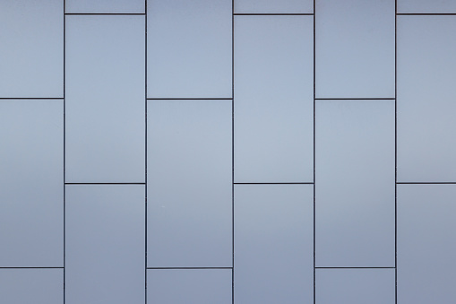 Outside wall of building covered with grayish blue painted metal rectangular panels - full-frame background and flat texture.