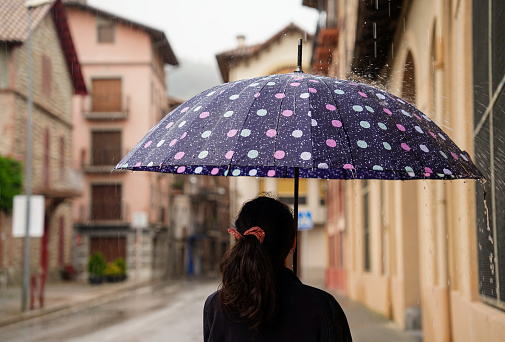 a tourist woman with an umbrella on a rainy winter day. rear view