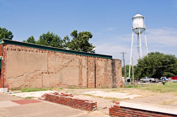 Remnants of a demolished building on Route 66 in Depew, Oklahoma. Blue sky and a white water tower in the background.
