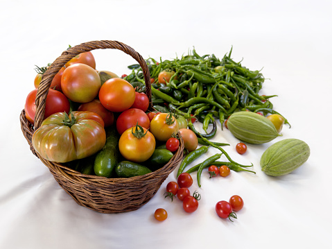 Fresh organic vegetables in wicker basket onwhite background