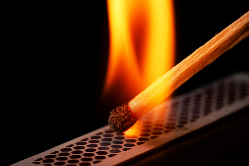 Firing point safety match. Close-up view to strike matches for matchbox. Detail of ignition matches for matchbox. Macro lighting of a match striking out a matchbox. Closeup safety match flame.