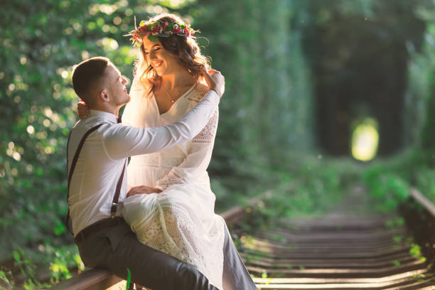 istock couple sitting and hugging on railway. tree tunnel. festive clot 1698620016