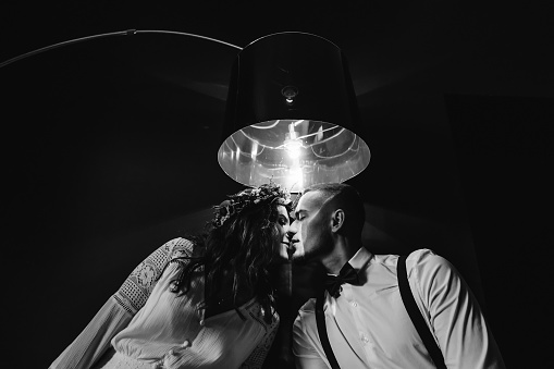 a couple in love kisses under a lamp on black and white photography
