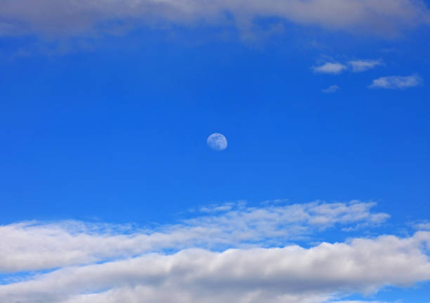 white moon on the blue sky in daytime and some clouds