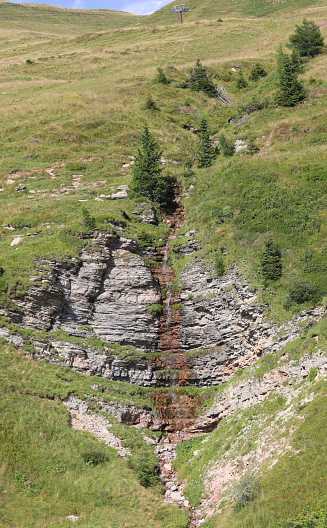 waterfall of spring water flowing between the rocks of the European Alps in summer