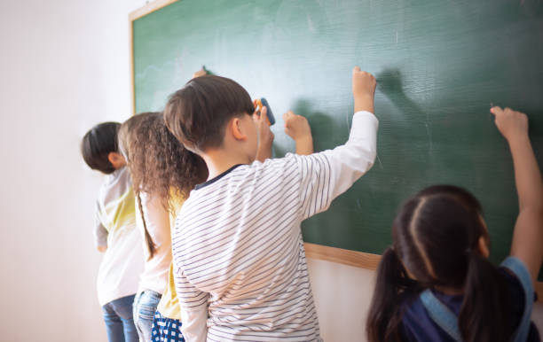 istock Group of Multi-ethnic happy Elementary school drawing on the chalkboard in classroom. Group of children pupils doing fun activity together at International School. Education knowledge concept 1698646249