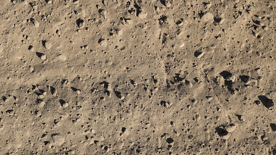 fragment of sandy earth with small lumps in bright sunlight view from the top angle, sandstone in golden brown color as a graphic resource and natural texture, climate change reflected in drought and drying out of the soil