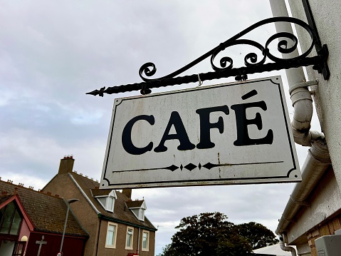 Low angle view of a street café sign with buildings in the background