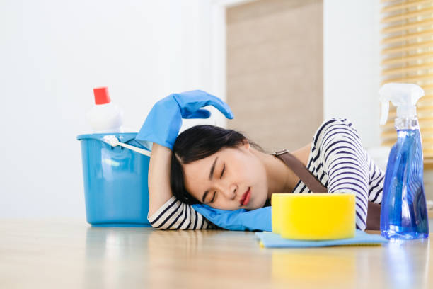 mulher jovem cansada sentada na sala de cozinha com produtos de limpeza e equipamentos, conceito de trabalho doméstico - home interior women domestic kitchen cabinet - fotografias e filmes do acervo