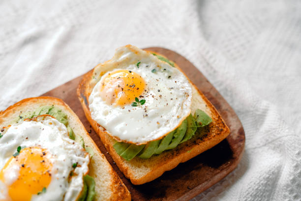 istock Toast with fried eggs and avocado on a wooden cutting board 1698676836