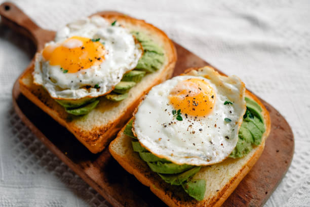 istock Toast with fried eggs and avocado on a wooden cutting board 1698676842