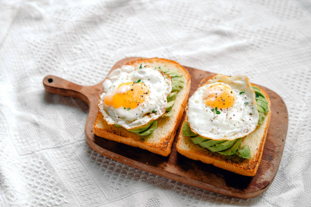 istock Toast with fried eggs and avocado on a wooden cutting board 1698676847
