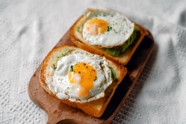 istock Toast with fried eggs and avocado on a wooden cutting board 1698676848