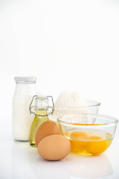 Wheat flour with eggs, oil and milk on table . White table Front view copyspace