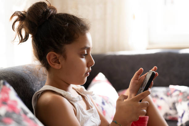 istock Young girl lying on sofa looking at smartphone. 1698687524