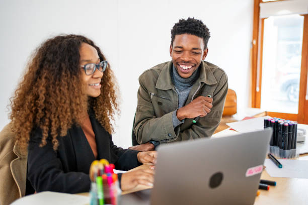 istock Two laughing young designers working on a laptop in their startup's office 1698689112