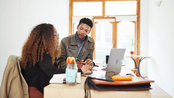 istock Young designers talking and using a laptop at an office desk 1698689767