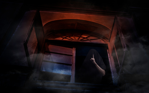 Grim reaper showing silence sign with finger standing in old ancient window castle, Halloween mystery concept