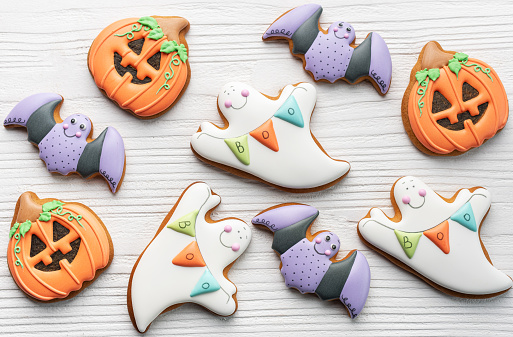 Multicolored Halloween homemade cookies on white wooden  background.