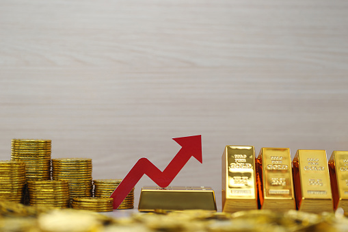 Red arrow graph on gold bar and gold coin money on natural green background, Business investment and Saving money for prepare in future concept