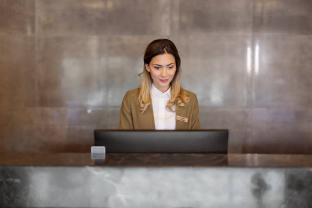 istock Beautiful Female Receptionist Working at Hotel Counter 1698741182