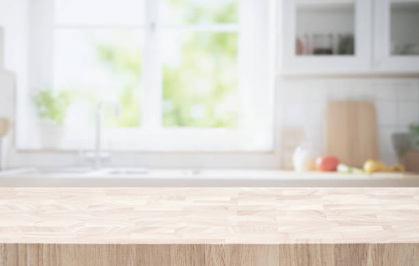 istock Selective focus.End grain wood table counter top on blur kitchen in morning window background. 1698753782