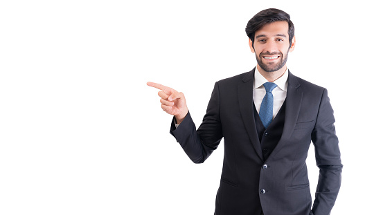 Portrait young successful stock market broker businessman isolated on white background Young successful business man smiling wearing suit with tie He pointing finger to copy space with smile face