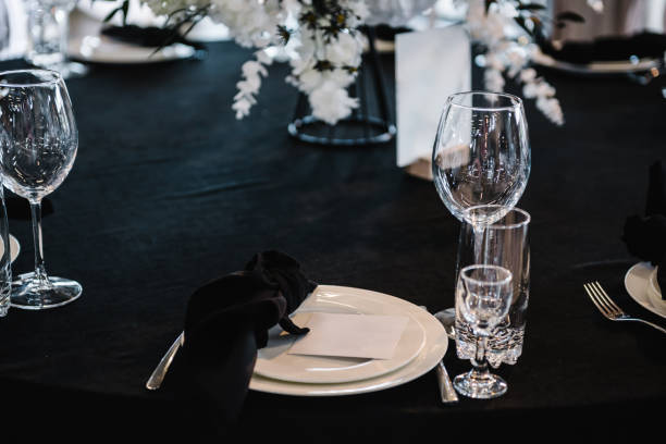 istock Serving, setting newlyweds table. Plate and glass, stack, wineglass, luxury rich decor, black napkin. Wedding set up, dinner table reception. Birthday, event. Restaurant interior. Side view. 1698767065