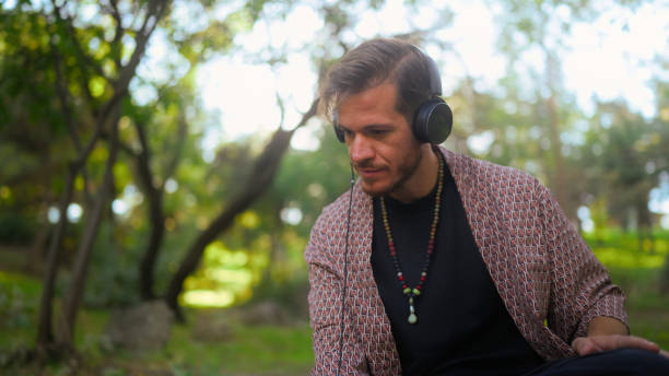 istock Man focusing on making music in public park 1698770946