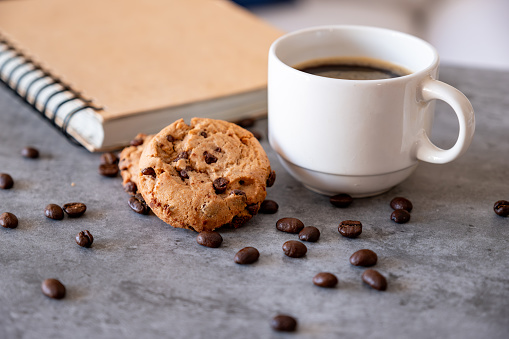 Cup of coffee with cookies and coffee beans on grey background  with not book