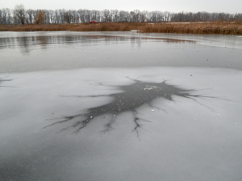 The picture shows the lake in winter. The surface of the water in the lake froze, forming an interesting pattern.