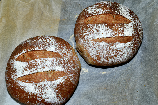 Loaf of home baked whole wheat bread on a plain white background decorated with sesame seeds.